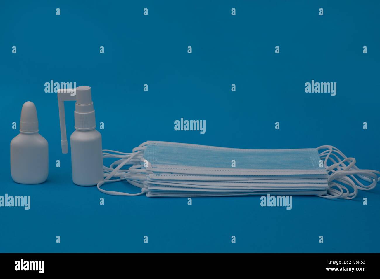 Una pila di maschere mediche, spray nasale, spray per la gola. Spazio vuoto Foto Stock