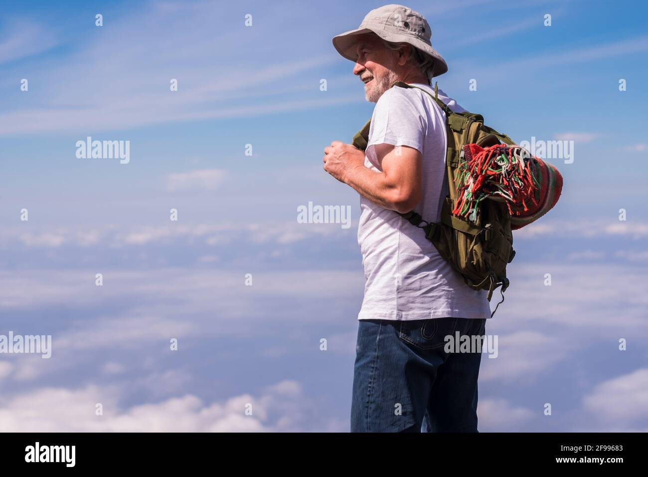 L'anziano attivo gode della libertà e del viaggio nella natura stile alternativo dello zaino in piedi con cielo blu e nuvole in background - giovani anziani maturi godere di trekking e. stile di vita sano all'aperto Foto Stock