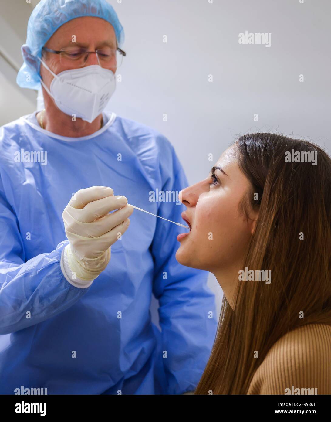 Essen, Nord Reno-Westfalia, Germania - Centro di test Corona Grugahalle aperto per il test cittadino gratuito, Covid Rapid test, un medico testa una giovane donna per il virus della corona utilizzando un tampone alla gola, dall'8 marzo, I cittadini tedeschi possono sottoporsi gratuitamente una volta alla settimana al centro di test rapido. Foto Stock