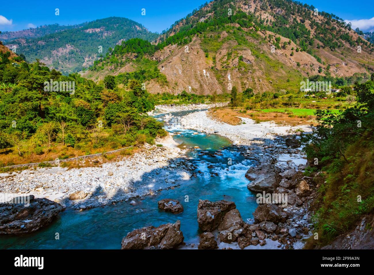 Vista del fiume Ranganga e la valle ai campi sullo sfondo del cielo blu e catene montuose dell'Himalaya, vicino Nainital, Uttarakhand, in Foto Stock