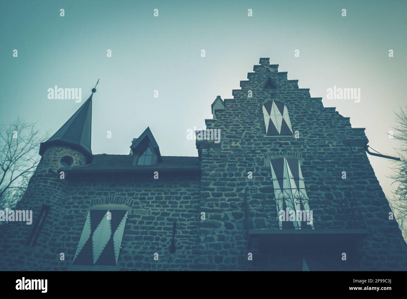 Una casa medievale con una torre, merli e finestre a bovindo e persiane chiuse. Malinconia, umore cupo Foto Stock