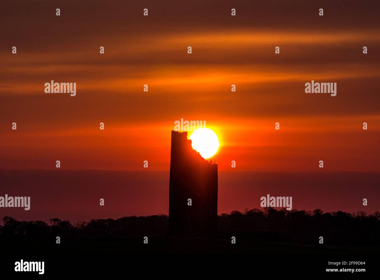 East Lothian, Scozia, Regno Unito, 17 aprile 2021. Regno Unito Meteo: Alba arancione sulla sagoma del mulino a vento di Balgone Barns. L'alba si rompe sulla torre in rovina del vecchio mulino a vento in pietra promettendo un giorno di primavera soleggiato Foto Stock