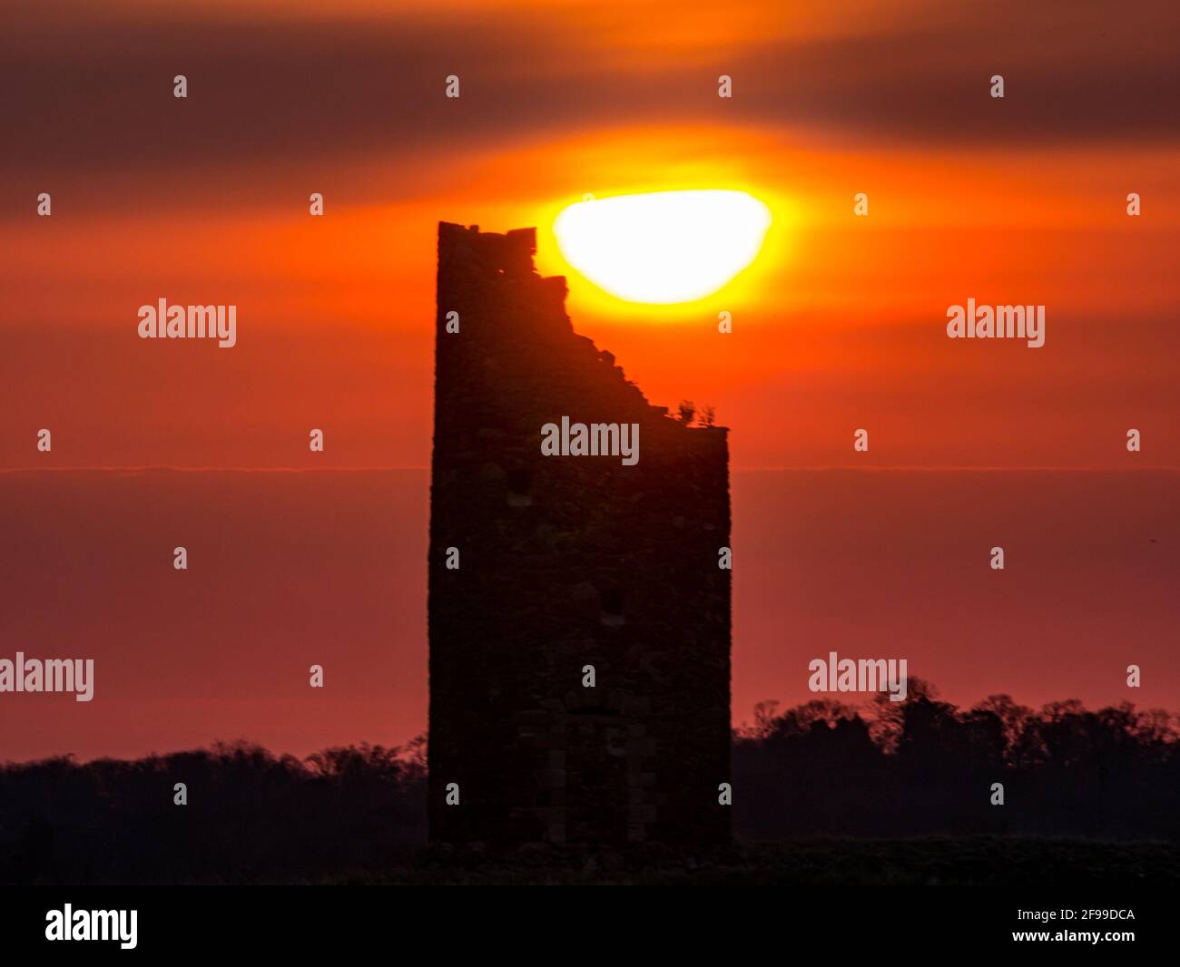 East Lothian, Scozia, Regno Unito, 17 aprile 2021. Regno Unito Meteo: Alba arancione sulla sagoma del mulino a vento di Balgone Barns. L'alba si rompe sulla torre in rovina del vecchio mulino a vento in pietra promettendo un giorno di primavera soleggiato Foto Stock