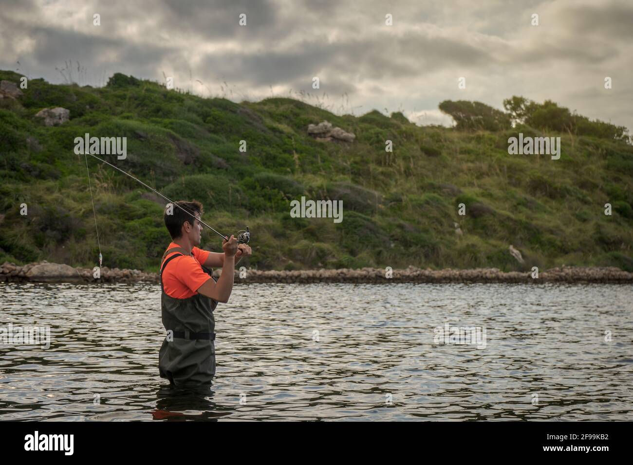 Wading pescatore circa per lanciare un'esca per catturare un pesce. Foto Stock
