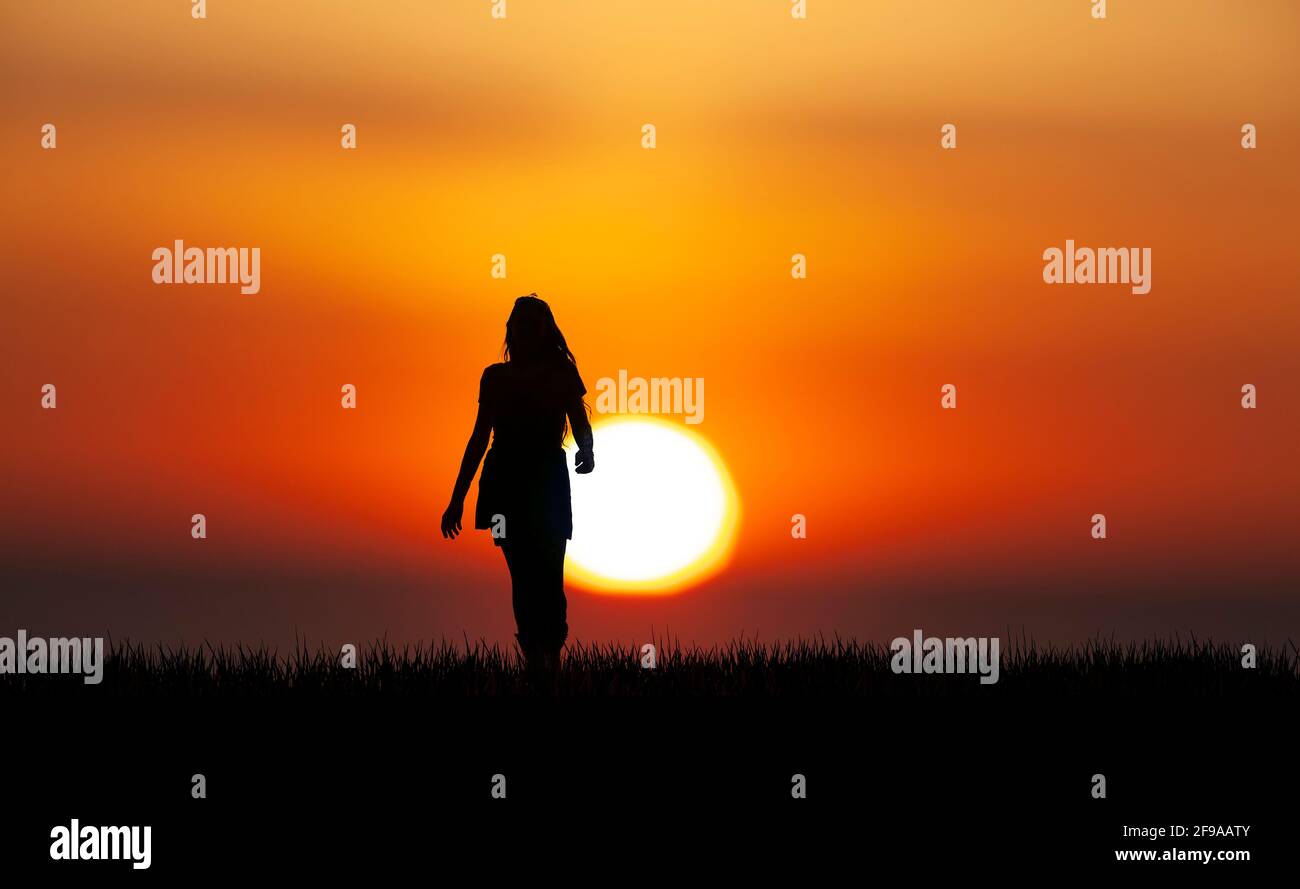 Silhouette di una donna con capelli lunghi prima del tramonto Foto Stock