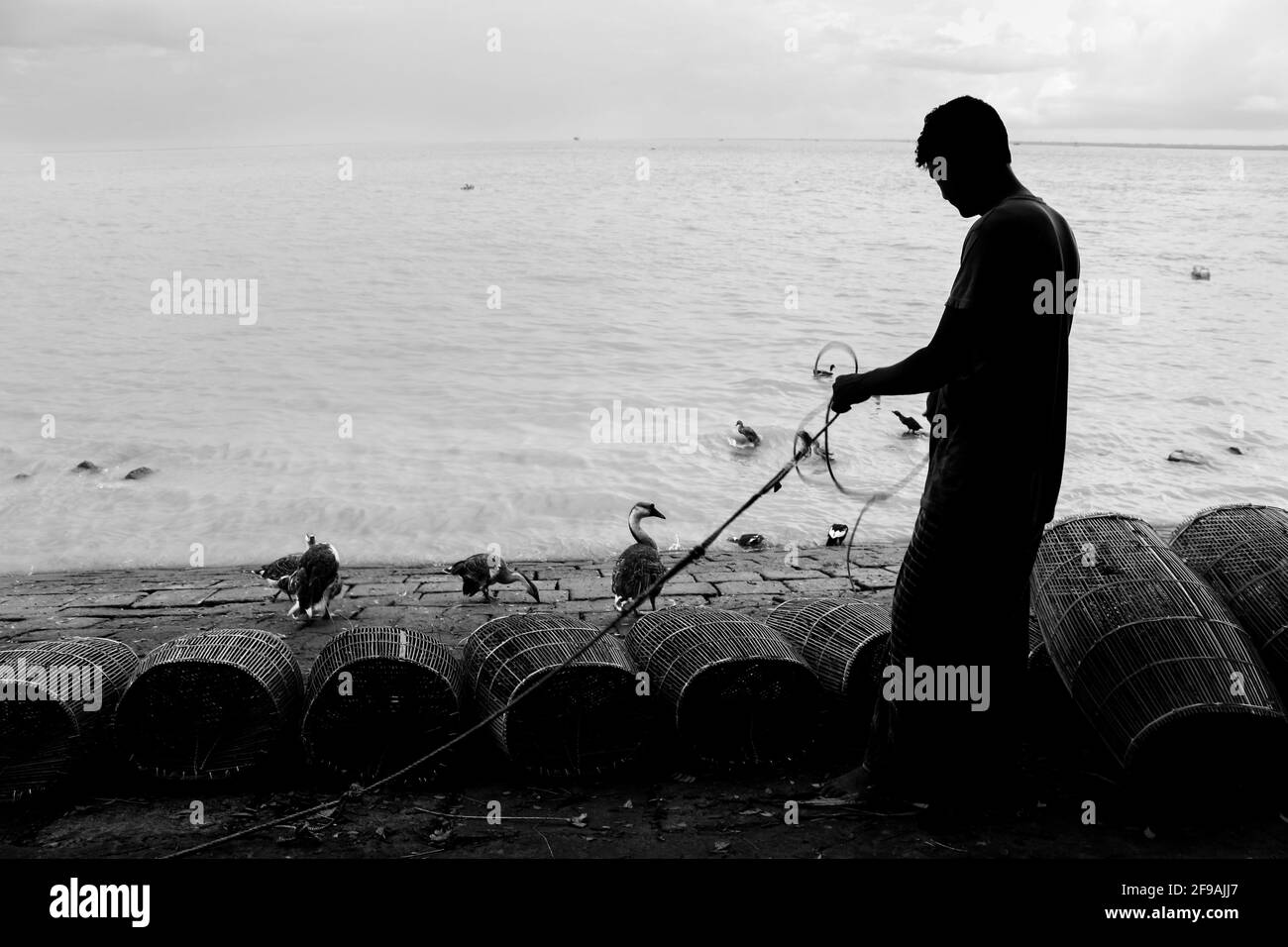 Pescatore in preparazione per la pesca con gabbia e corda sulla riva del fiume ho catturato questa immagine il 15 settembre 2020 da Chandpur, Bangladesh Foto Stock