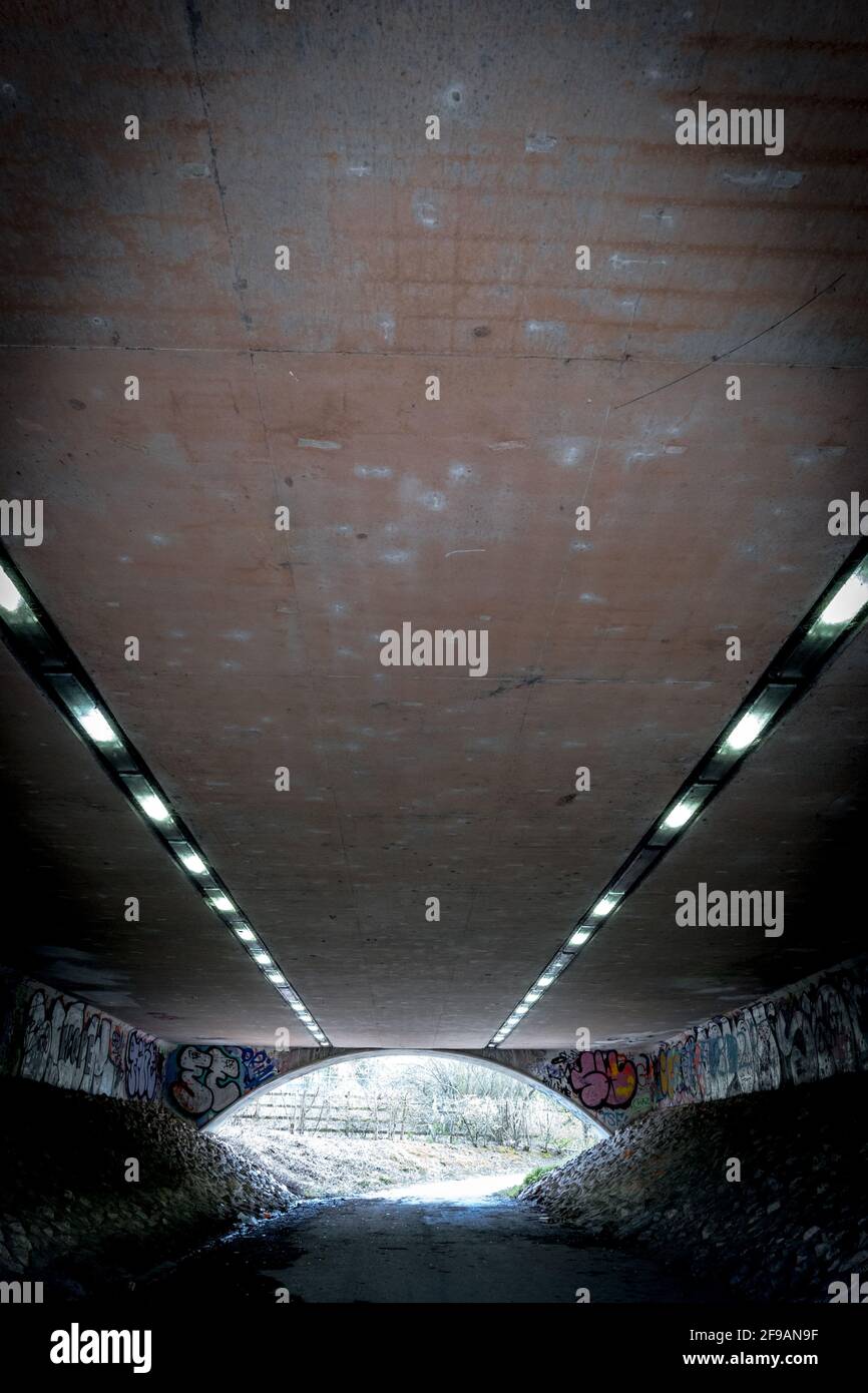 Illuminazione a striscia che illumina un sottopassaggio predestiano con graffiti. Foto Stock