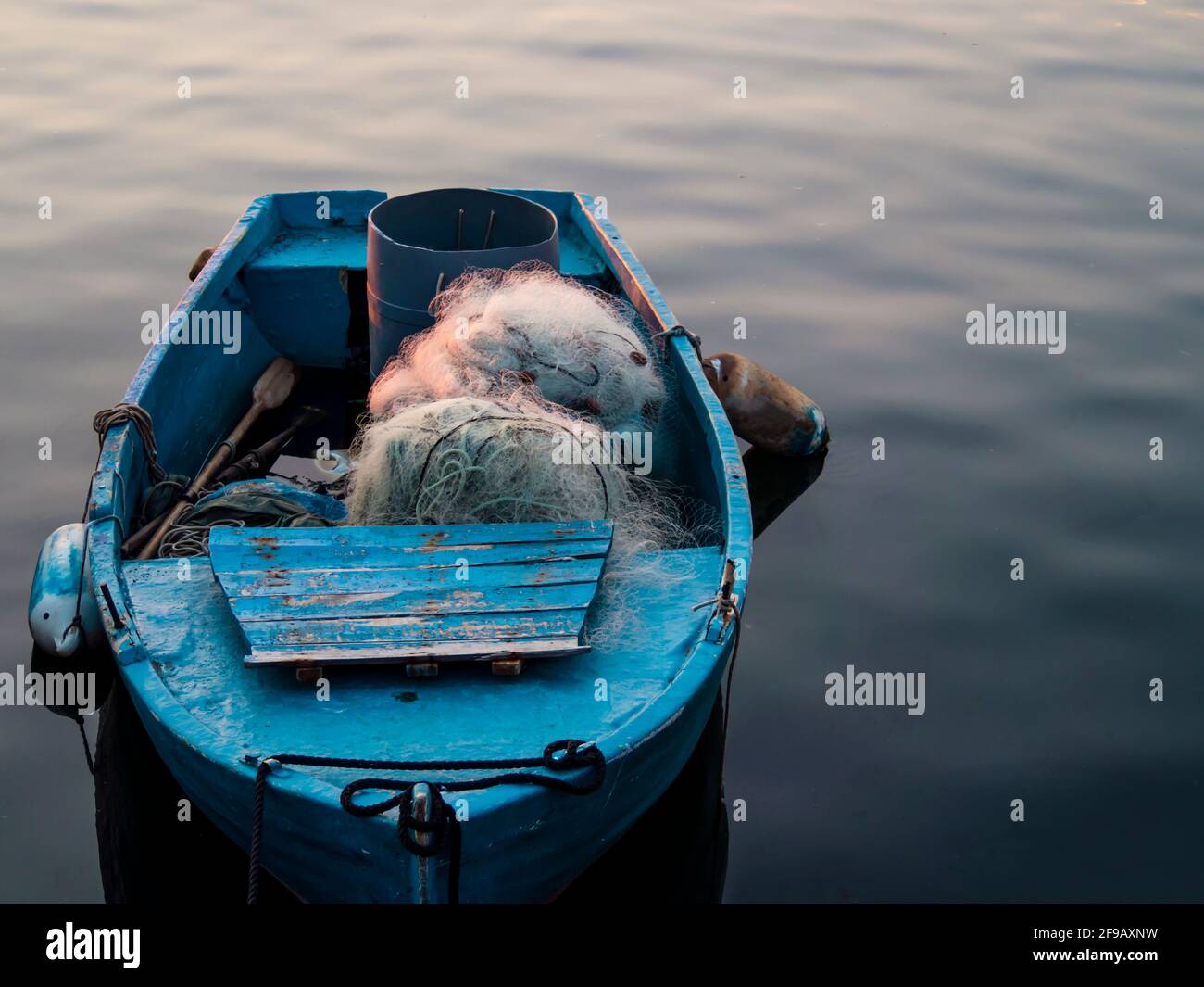 Tipica barca di pescatori con reti e remi di legno ormeggiati un molo Foto Stock