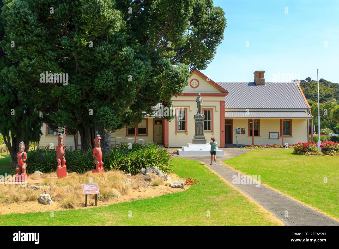 Lo storico tribunale di Coromandel, Nuova Zelanda, costruito nel 1873. Nel giardino si trova una collezione di figure intagliate Maori Foto Stock