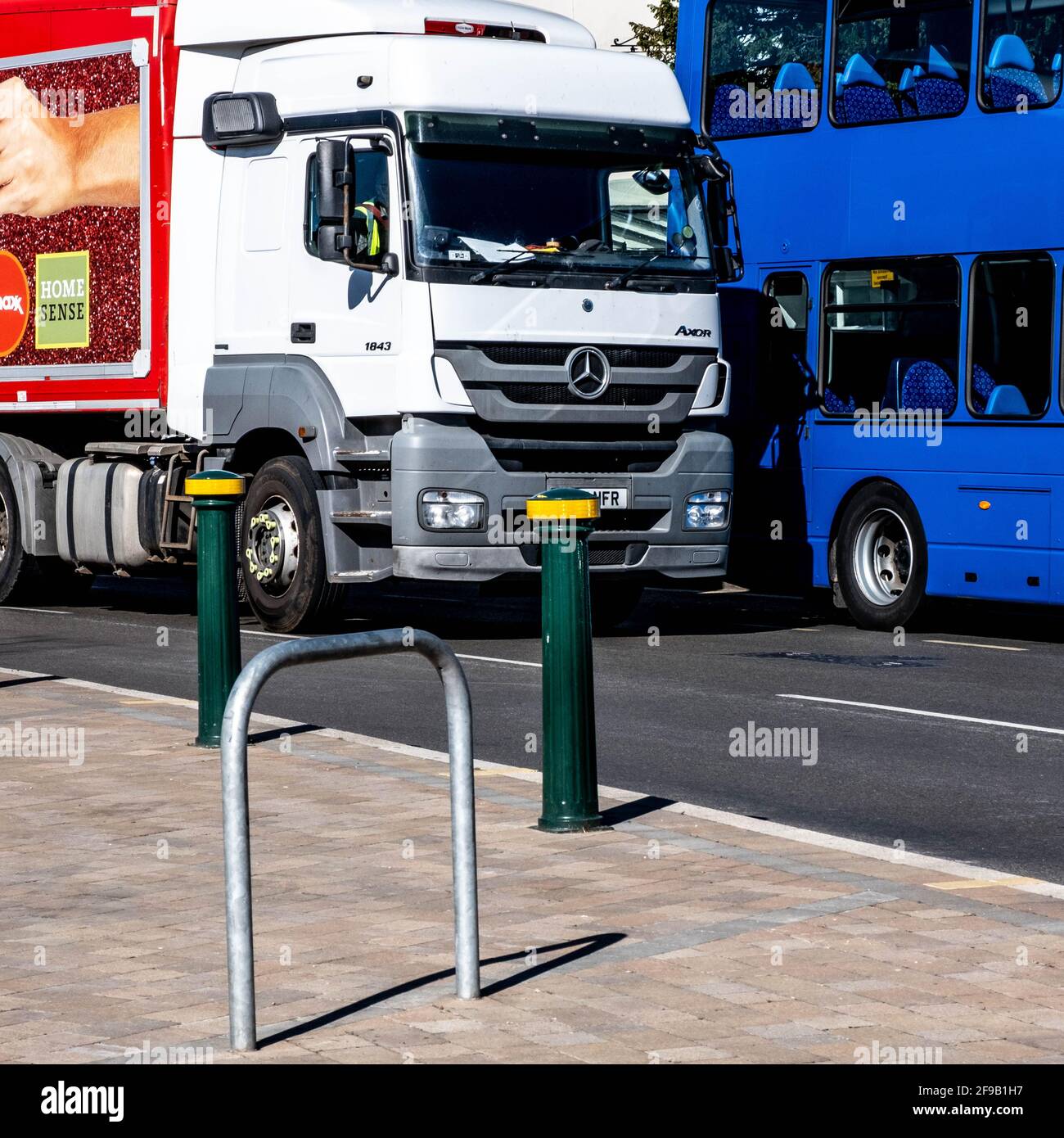 Epsom London UK, aprile 17 2021, veicolo per merci pesanti che passa davanti A un autobus pubblico per i trasporti pubblici blu parcheggiato su una High Street Foto Stock