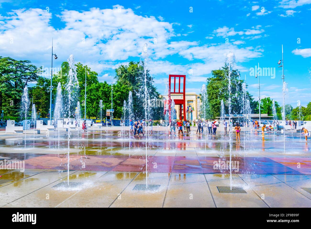 GINEVRA, SVIZZERA, 20 LUGLIO 2017: I turisti ammirano la scultura di una sedia rotta di Daniel Berste di fronte al Palazzo delle Nazioni di Ginevra, Foto Stock