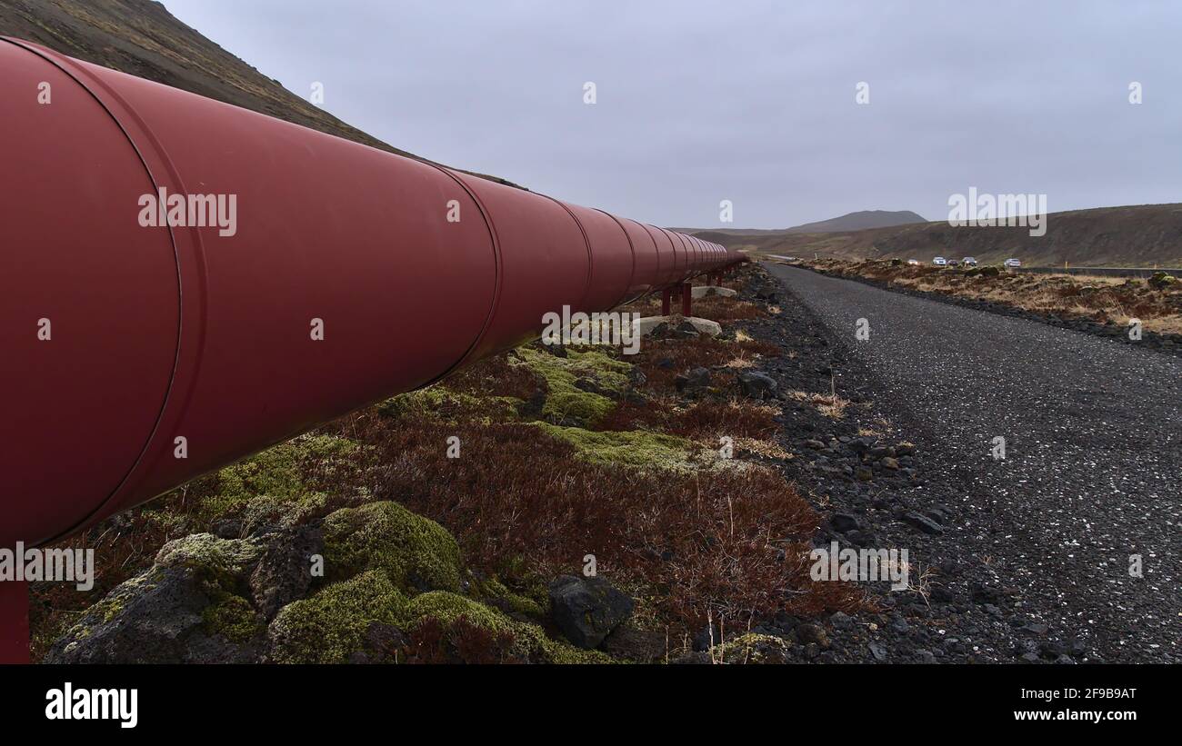 Tubazione in metallo di colore rosso per il trasporto di acqua calda dalla centrale di Svartsengi al villaggio di Grindavik sulla penisola di Reykjanes, Islanda. Foto Stock