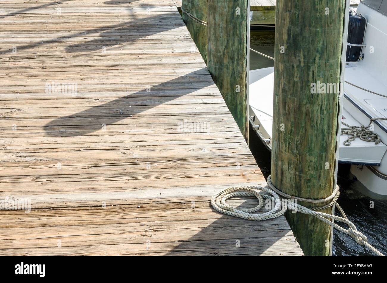 Particolare di un molo in legno con una corda legata ad un posto di ormeggio Foto Stock