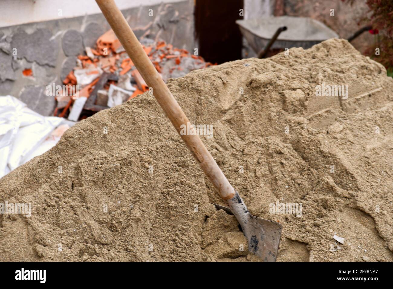 Primo piano di una pala bloccata in un mucchio di sabbia su un cantiere Foto Stock