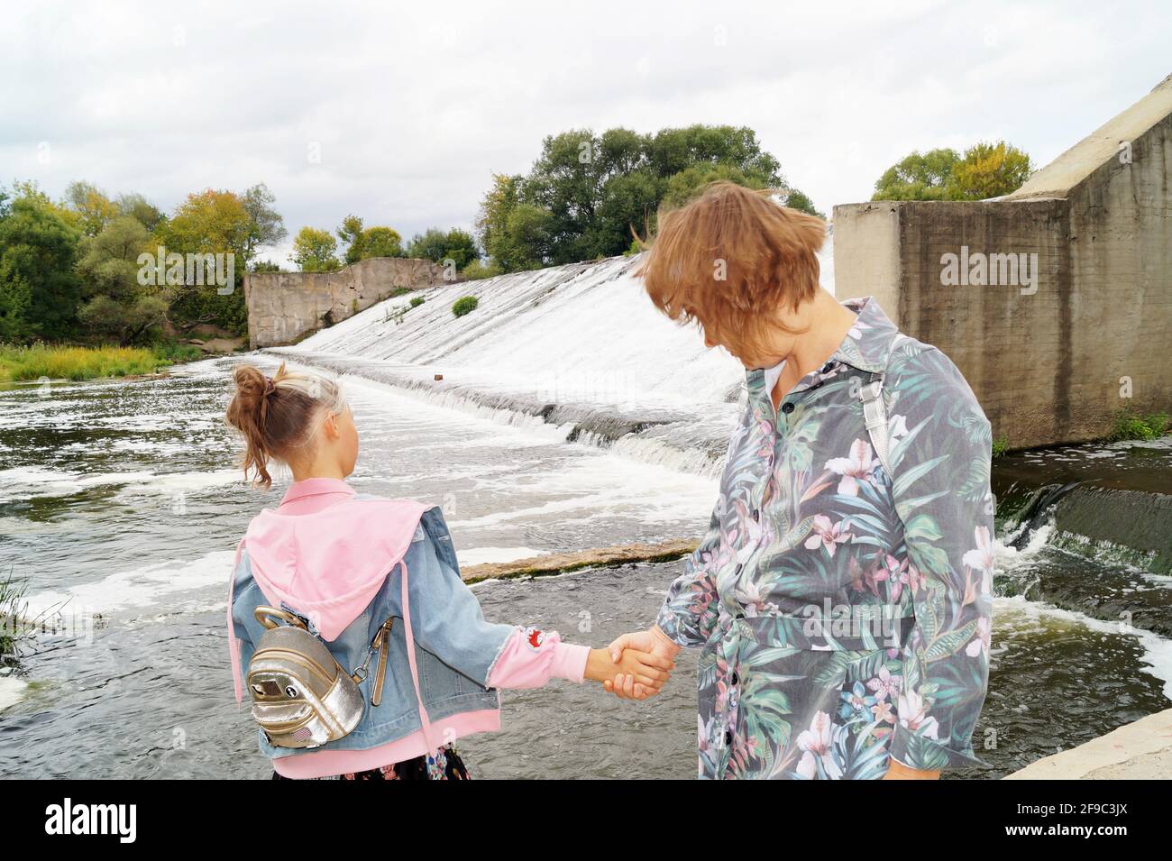 Madre e figlia tengono le mani sulla diga Foto Stock