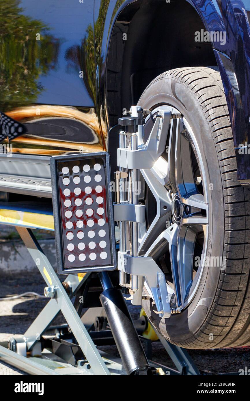 La vettura si trova su un cavalletto con sensori di campanatura delle ruote. Attrezzatura per l'allineamento delle ruote di un'auto su un cavalletto mobile. Immagine verticale, spazio di copia. Foto Stock