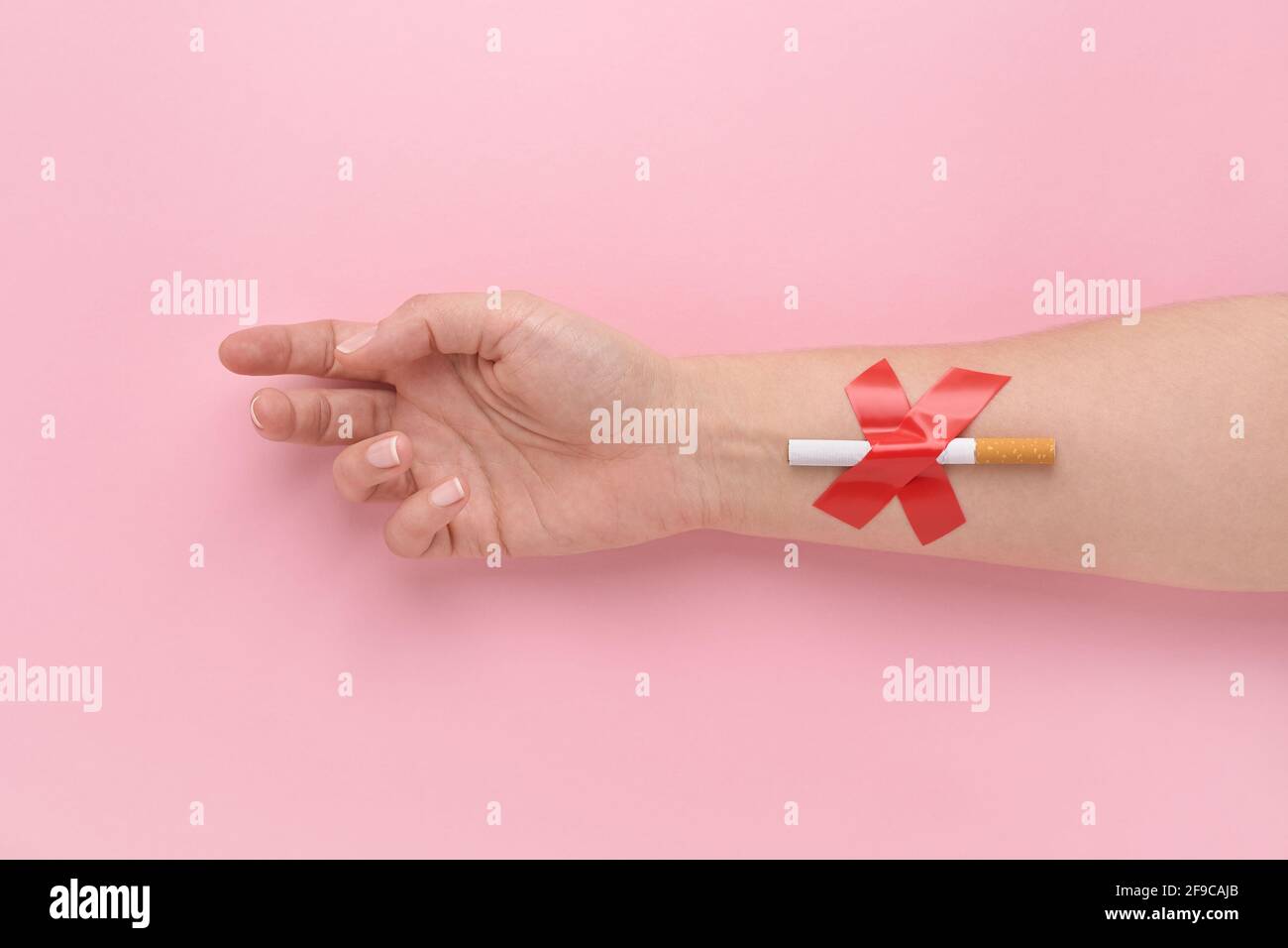 Una sigaretta incollata con una croce alla mano di una donna, smettere di fumare concetto. Foto Stock