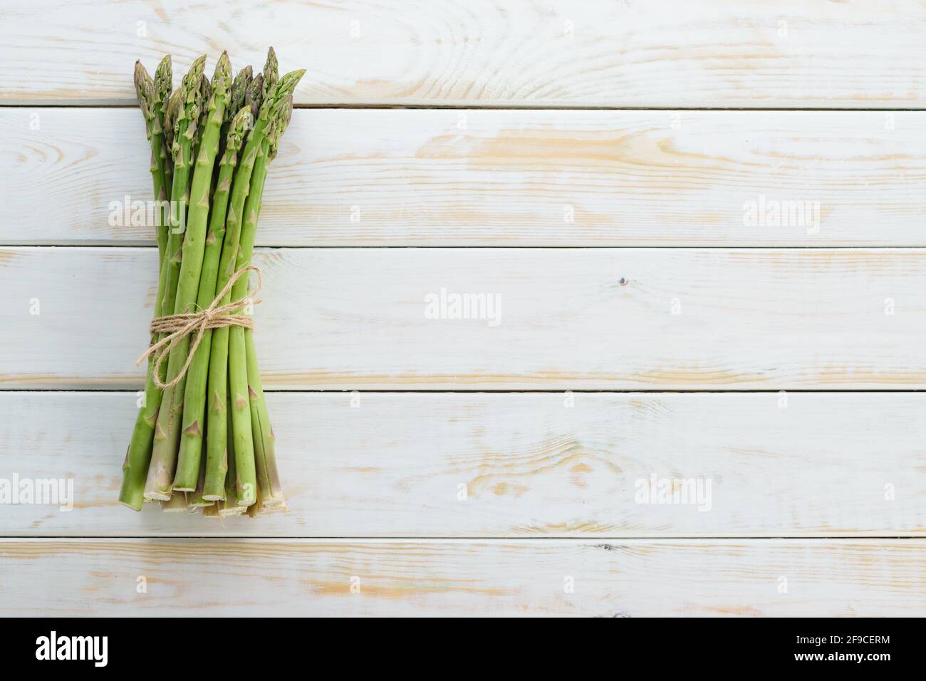 Vista dall'alto di un mazzo di asparagi freschi crudi legati uno spago per tela su un tavolo rustico in legno (spazio per la copia) Foto Stock