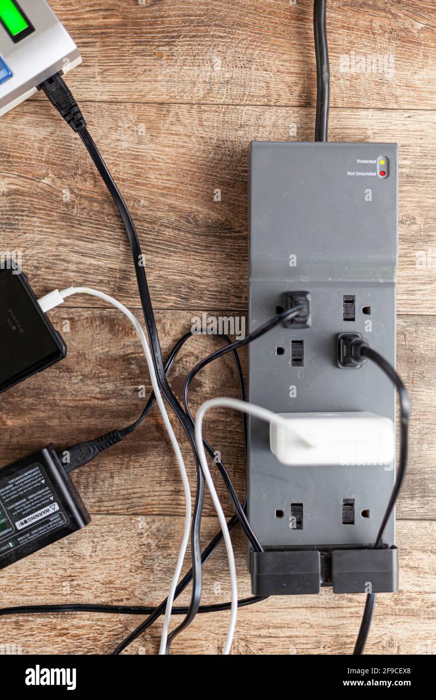 Primo piano vista dall'alto di una basetta di alimentazione a filo con protezione da sovratensioni. Più dispositivi elettronici sensibili sono collegati a prese singole e Th Foto Stock