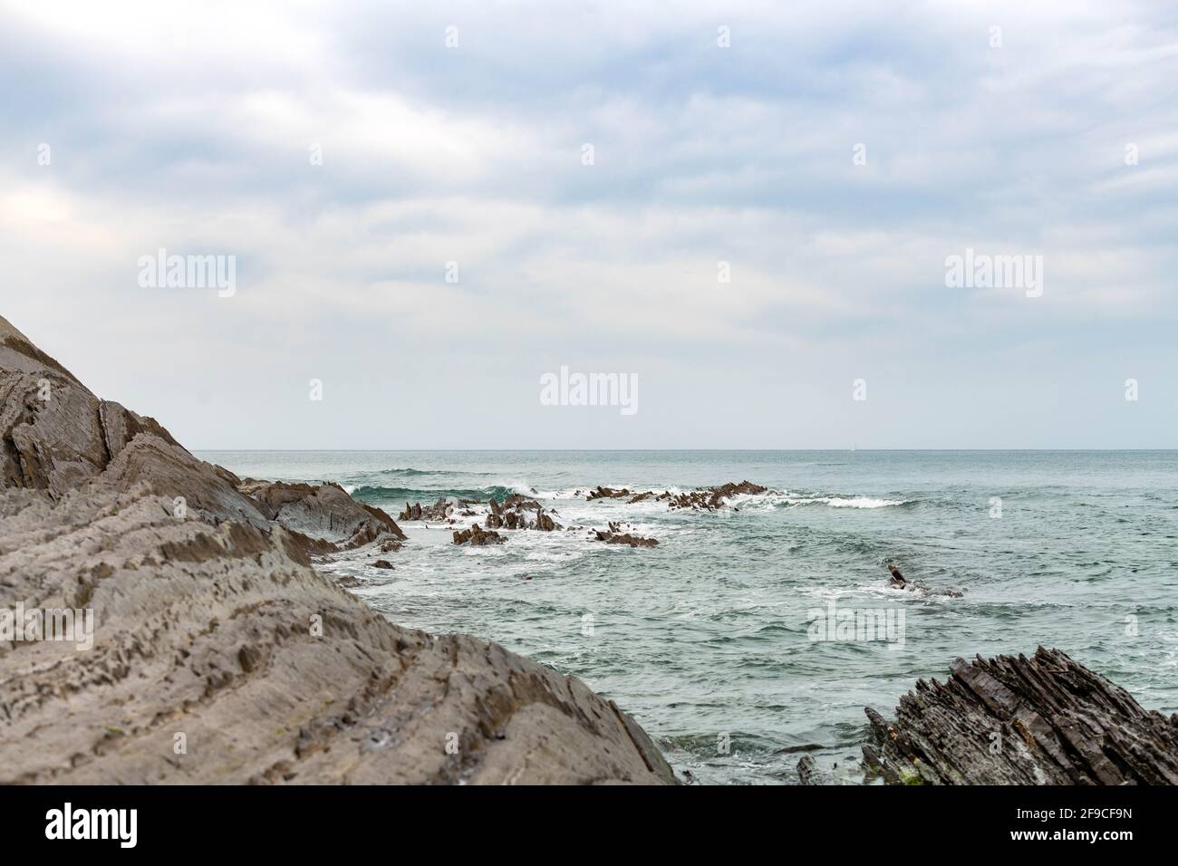 Sakoneta spiaggia nel nord della Spagna piena di rocce affilate emergenti dal fondo dell'oceano Foto Stock