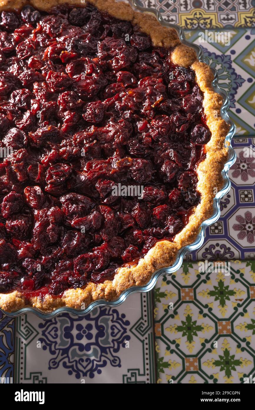 Cherry Pie vista dall'alto. Cottura fatta in casa. Crostata aperta rotonda con riempimento. Versare i dolci sulla tavola di piastrelle colorate Foto Stock