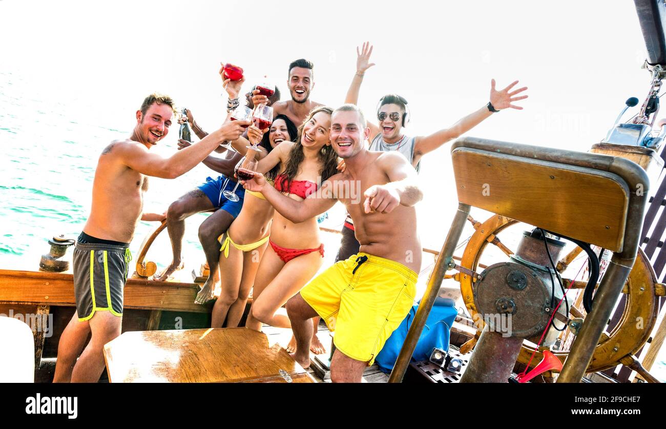 Gruppo di amici milleniali multirazziali che si divertono a fare il tifo alla barca a vela Festa - concetto di amicizia con giovani multirazziali su barca a vela di lusso Foto Stock
