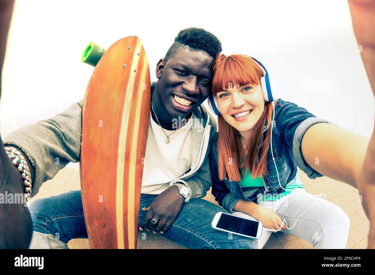 Hipster coppia multirazziale in amore prendendo selfie su sfondo bianco - concetto di divertimento con tendenze alternative della moda e della tecnologia Foto Stock