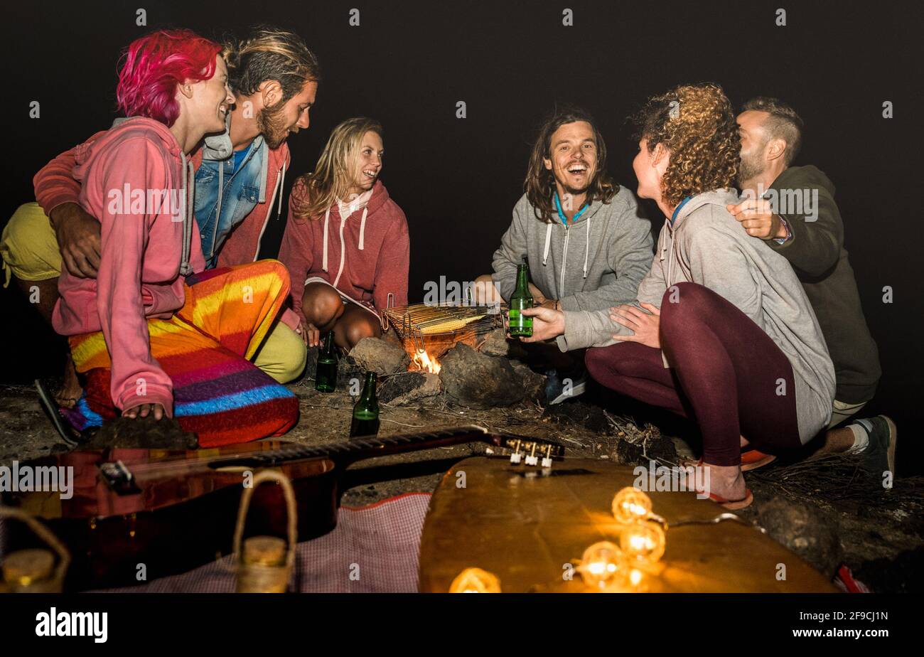 Giovani amici hippie divertirsi insieme a Beach camping party Con il barbecue di notte del campeggio - concetto di viaggio di amicizia con il surfer giovane persone Foto Stock