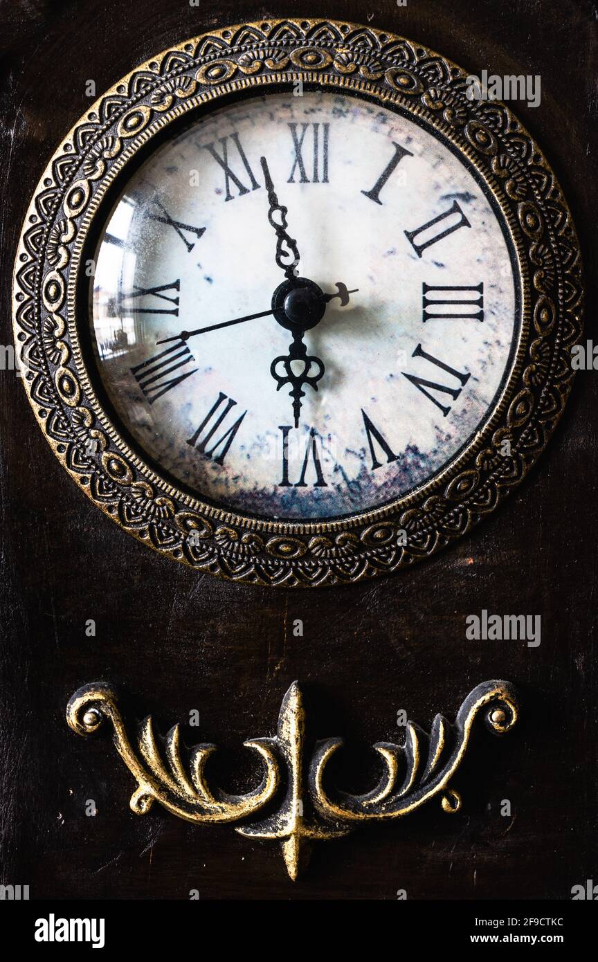 Primo piano immagine di un antico orologio faccia e metallo decorazione sotto su uno sfondo scuro. L'ora viene visualizzata alcuni minuti prima di 6 e include un secondo Foto Stock