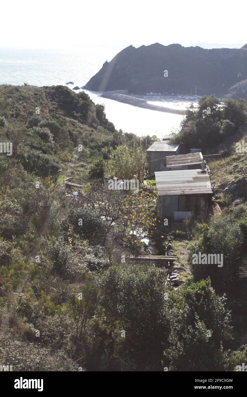 Capanne in ferro corrugato in una valle con vista sull'oceano Foto Stock