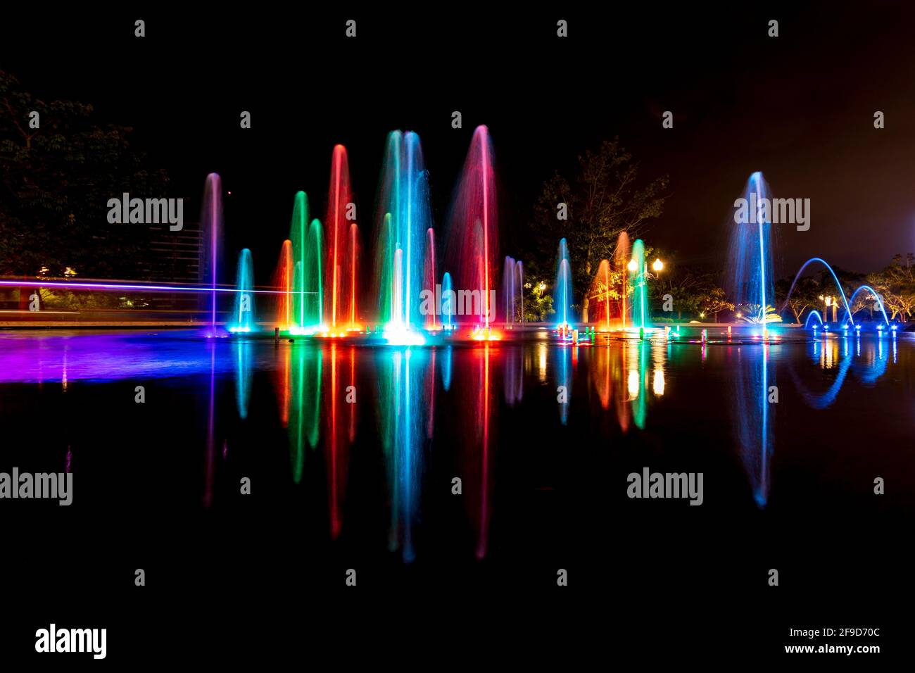 Lunga esposizione di una fontana all'aperto multicolore - acqua e luce che si muovono alla musica - esperienza di shopping unica a Merida, Messico Foto Stock