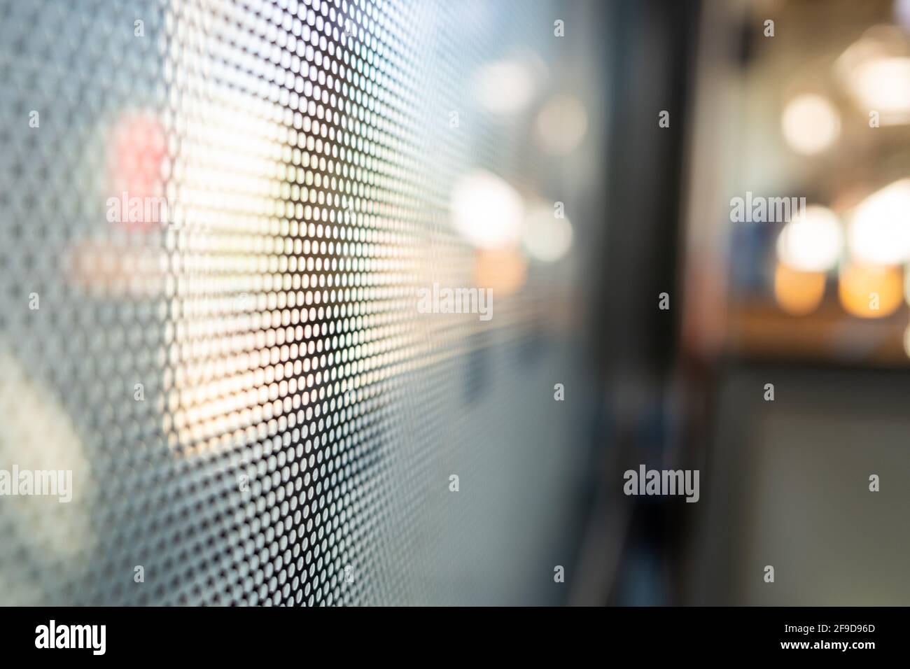 Vista ravvicinata della pellicola adesiva One Way Vision con motivo a punti sul vetro della finestra del treno e sfondo sfocato del treno passeggeri e del bokeh. Foto Stock