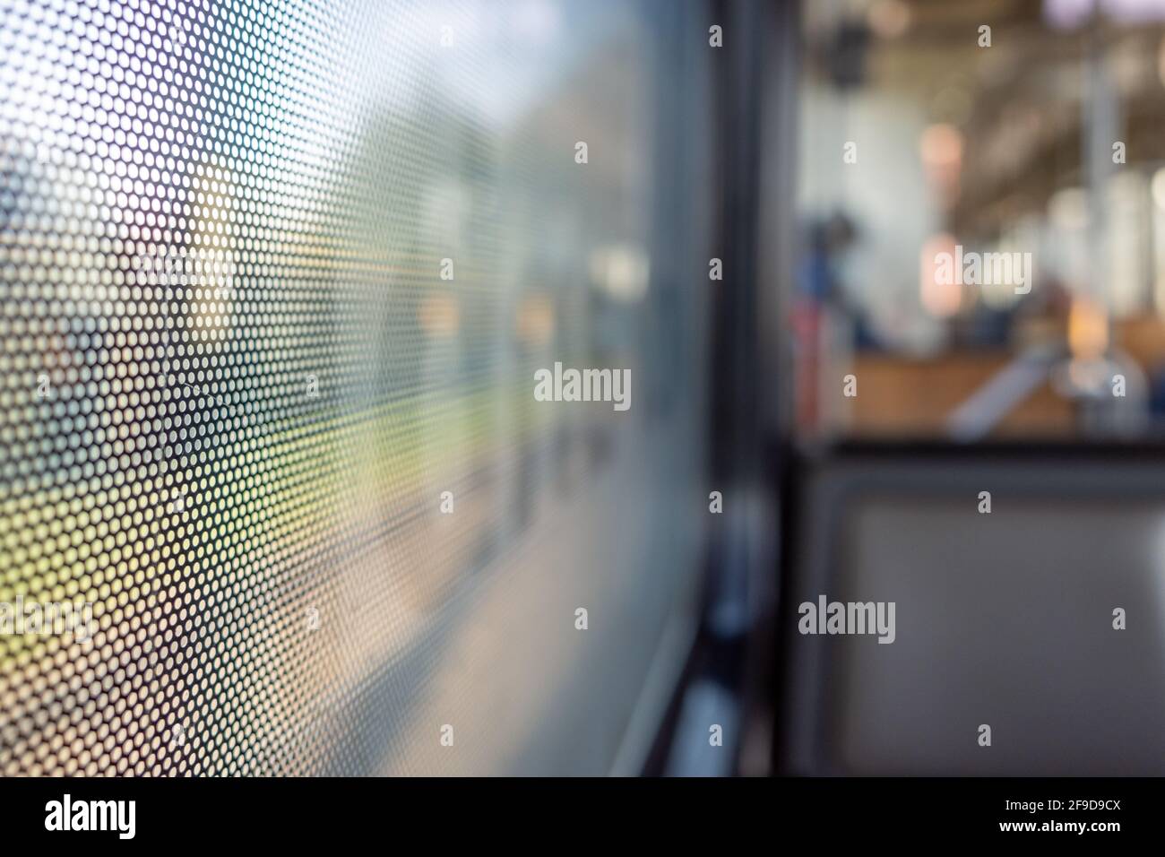 Vista ravvicinata della pellicola adesiva One Way Vision con motivo a punti sul vetro della finestra del treno e sfondo sfocato del treno passeggeri e del bokeh. Foto Stock