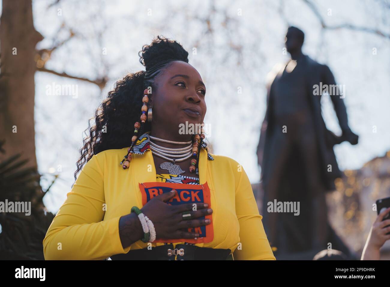 Westminster, Londra | UK - 2021.04.17: Lady in costume giallo con Black Lives Matter segno dando una spionata alla protesta di Kill the Bill Foto Stock