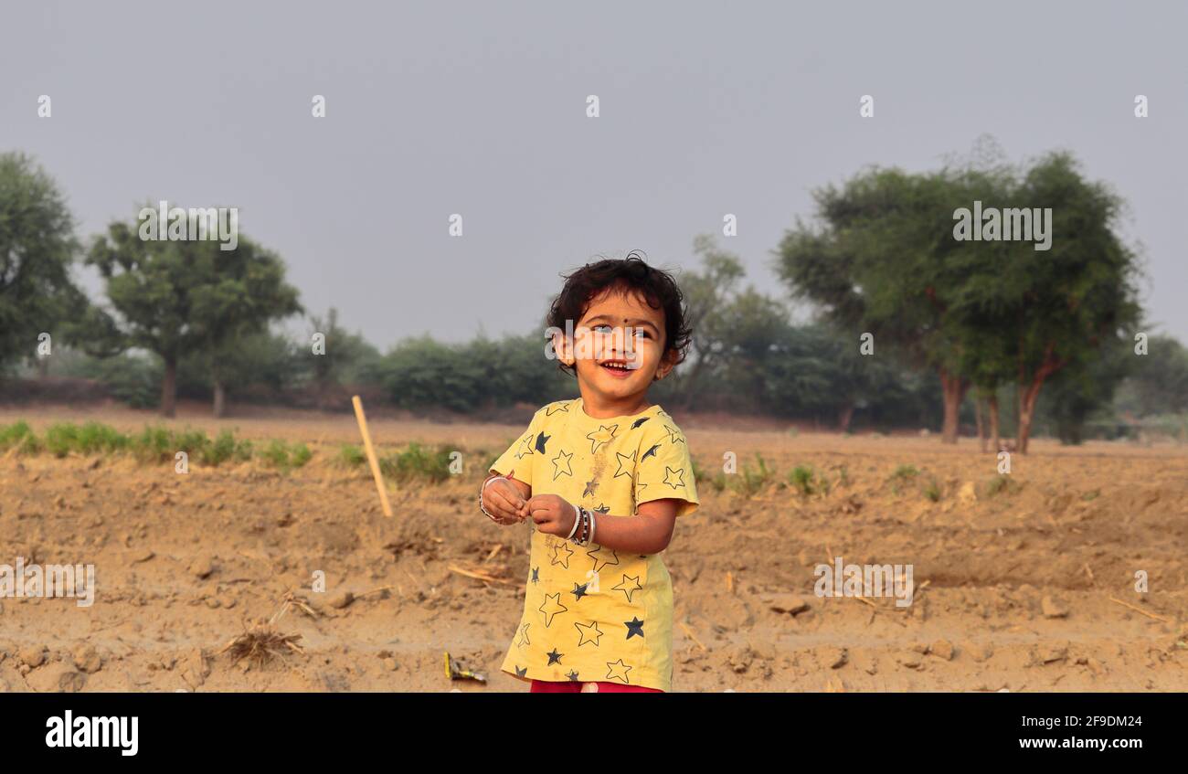 Primo piano di un ragazzino indiano sorridente e in piedi nel settore agricolo Foto Stock