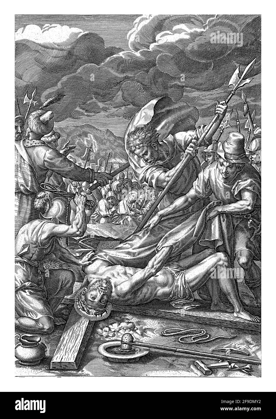 Cristo è sulla croce. Un certo numero di soldati stanno strappando i suoi vestiti fuori del suo corpo. Accanto a lui ci sono tutti i chiodi e un martello. La folla sta guardando. Foto Stock