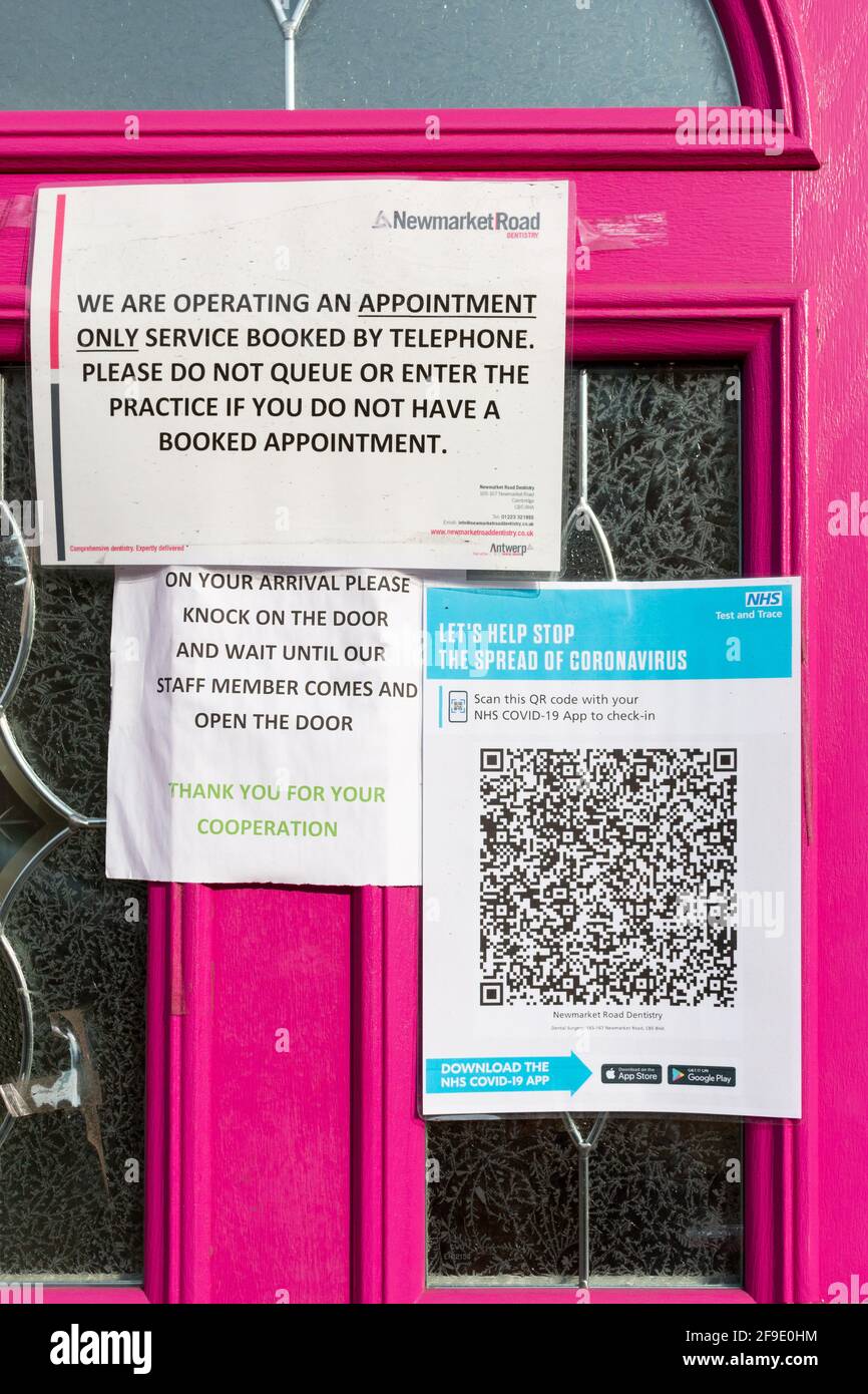 I cartelli informativi di Covid-19 e il codice QR dell'app Test and Trace coprono le finestre della porta rosa dell'ufficio del dentista su Newmarket Road, Cambridge, Regno Unito. Foto Stock