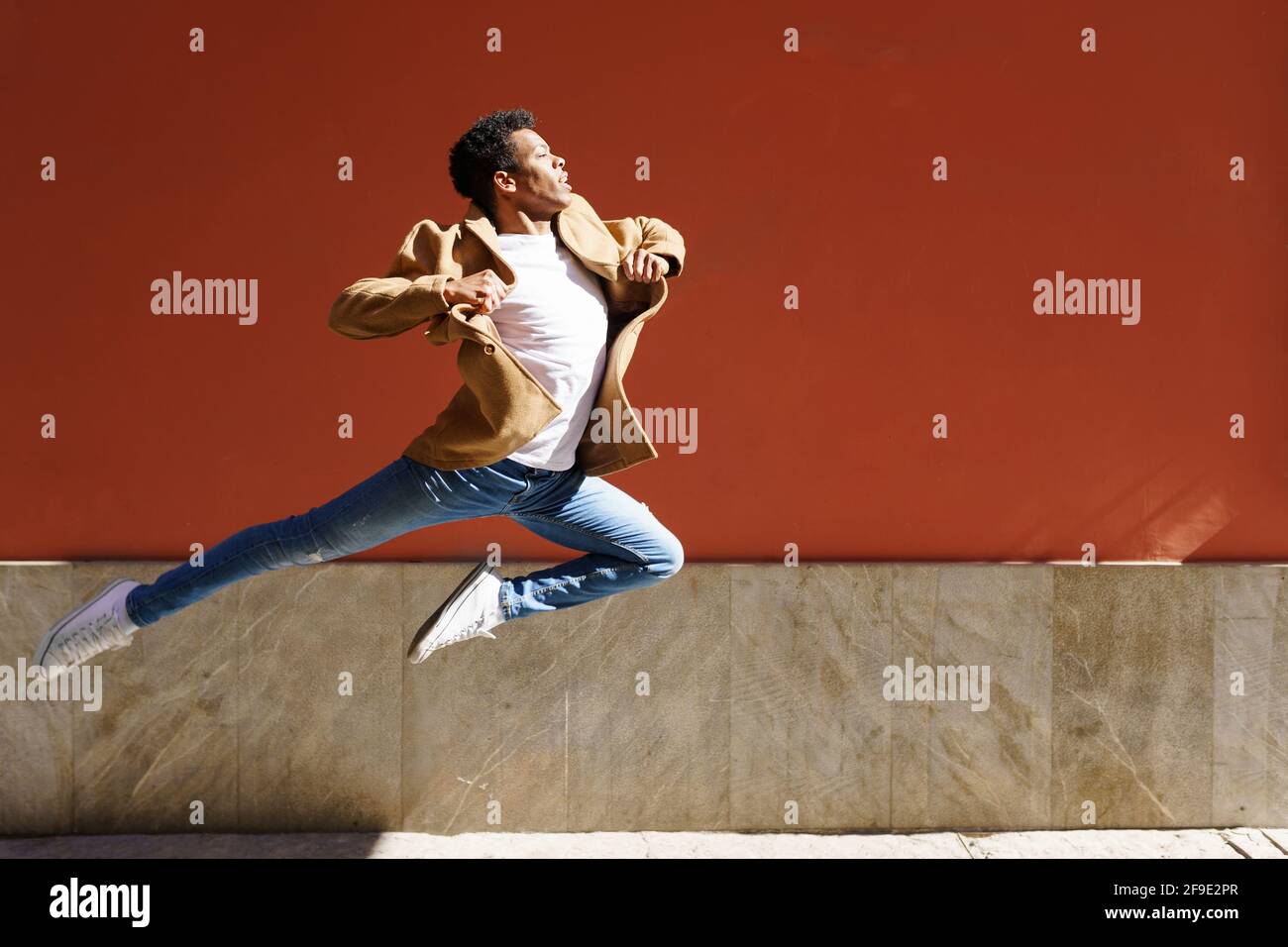 Giovane uomo nero che fa un salto acrobatico nel mezzo della strada. Foto Stock