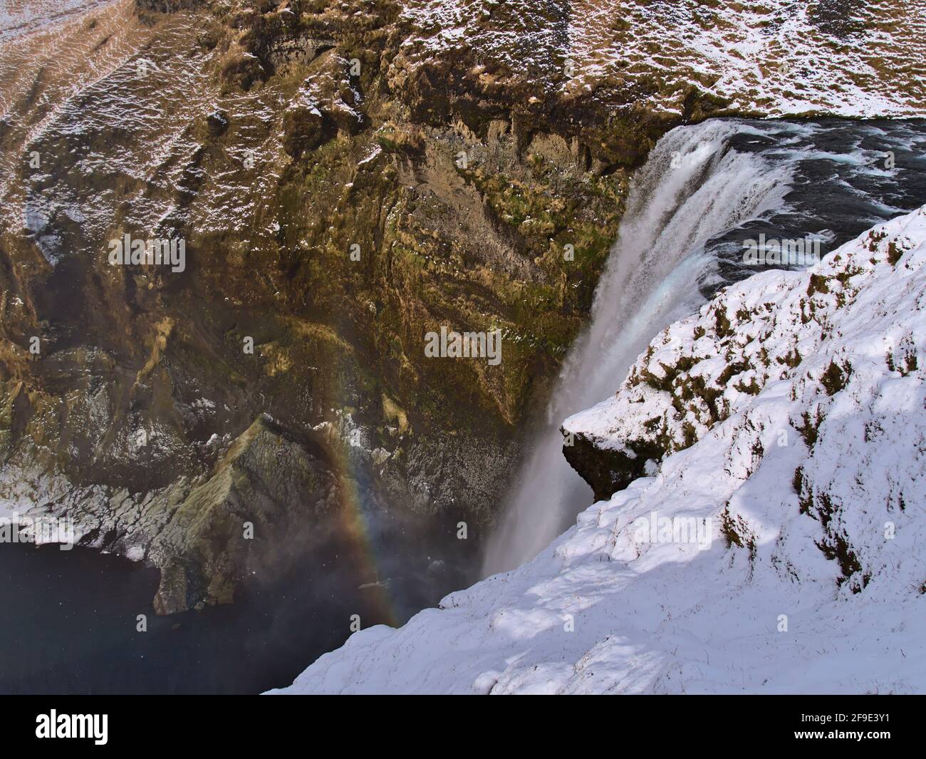 Parte superiore della famosa cascata Skógafoss, una popolare destinazione turistica nel sud dell'Islanda vicino alla circonvallazione, nella stagione invernale con colorato arcobaleno. Foto Stock