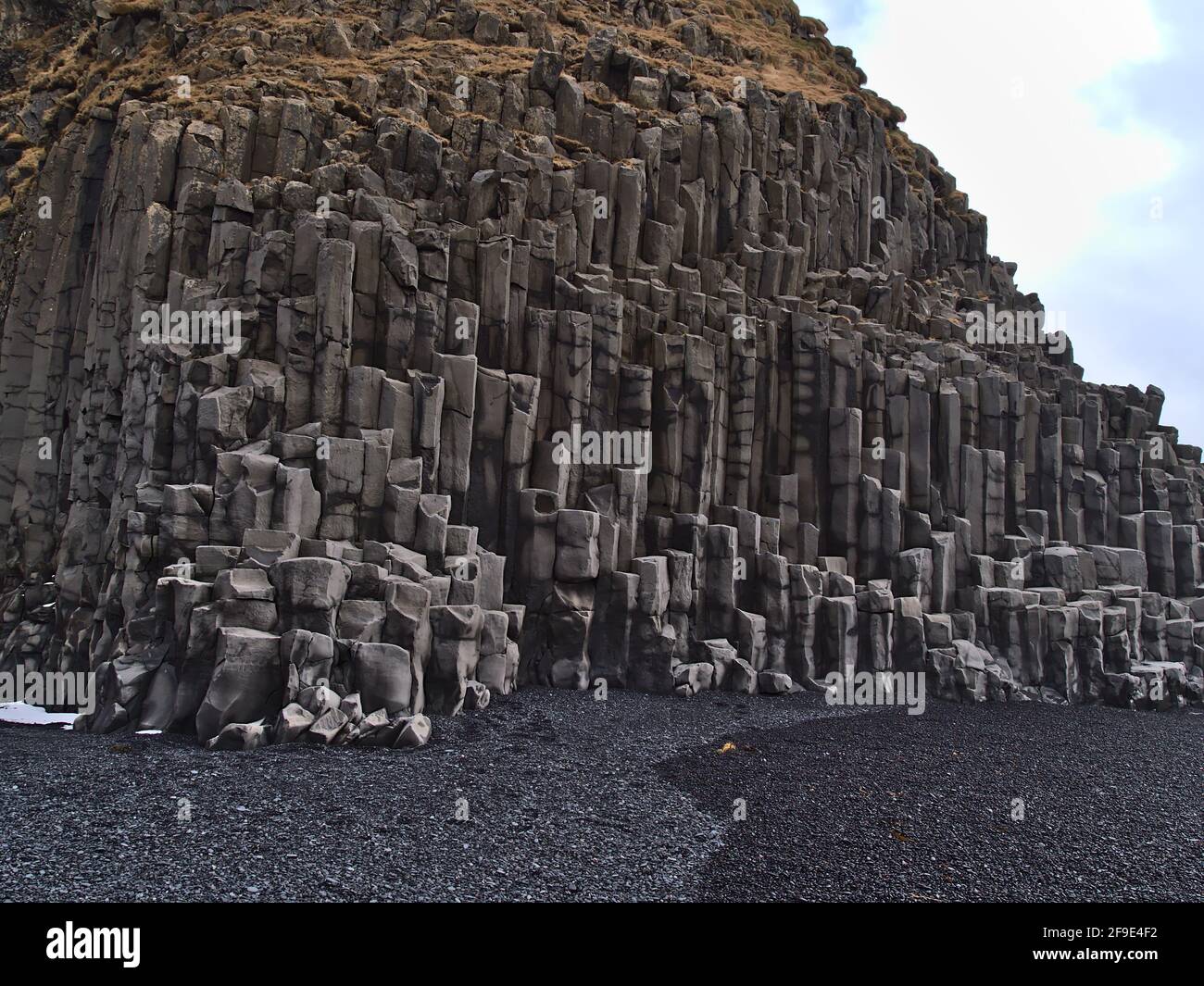 Vista delle formazioni rocciose basaltiche sulla famosa spiaggia di Reynisfjara con pietre di ciottoli nere sulla costa meridionale dell'Islanda in inverno. Foto Stock