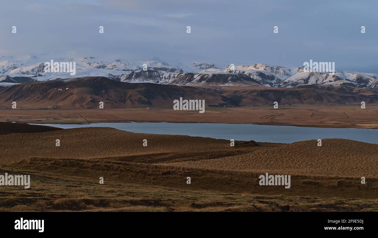 Splendida vista panoramica sulle colline innevate della calotta di ghiaccio Mýrdalsjökull, che copre il vulcano Katla, alla luce della sera vista da Dyrhólaey, Islanda. Foto Stock