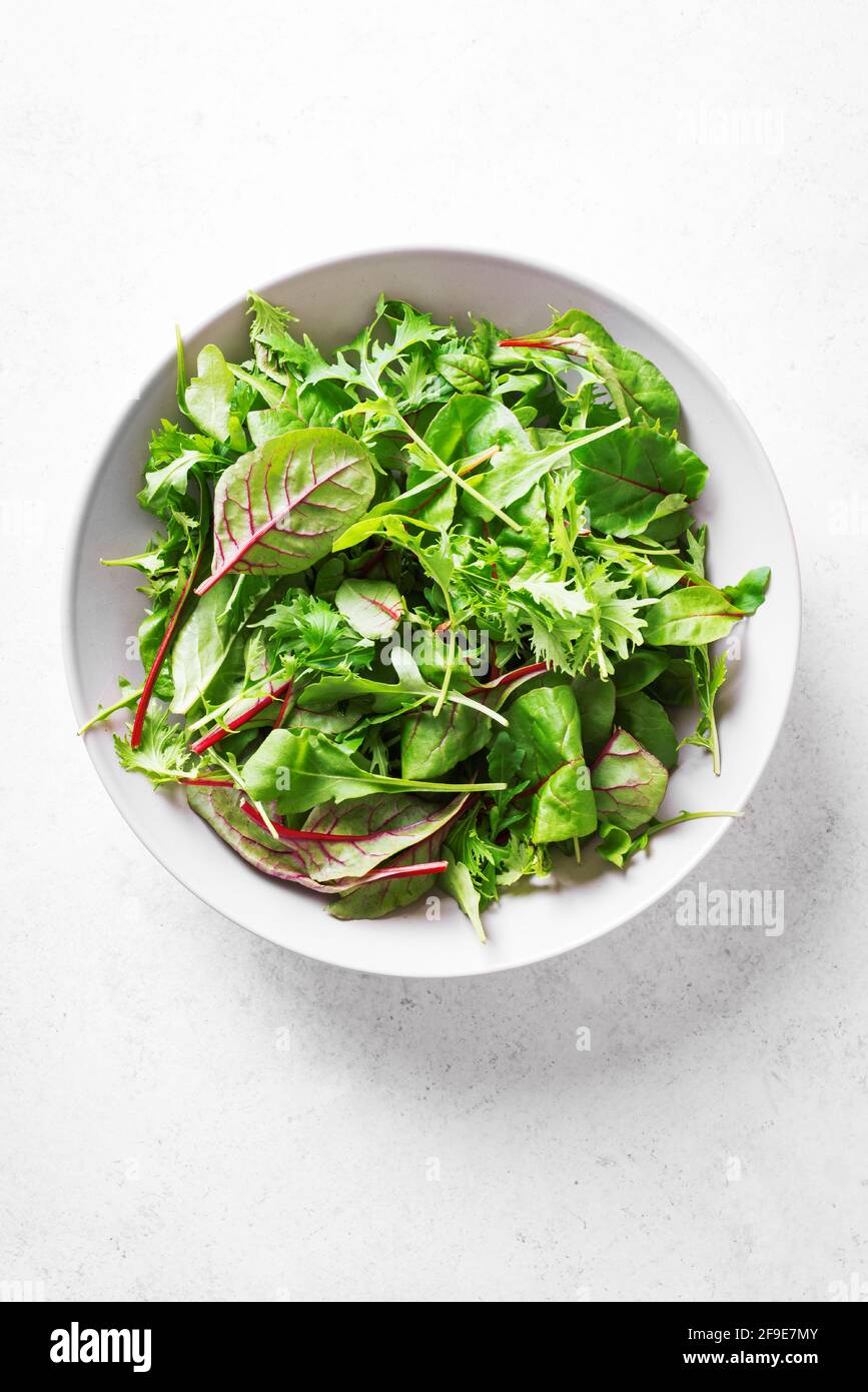 Insalata verde biologica, foglie fresche mescolano insalata con rucola, bietola svizzera e lattuga su sfondo bianco, vista dall'alto, spazio copia. Mangiare sano. Foto Stock