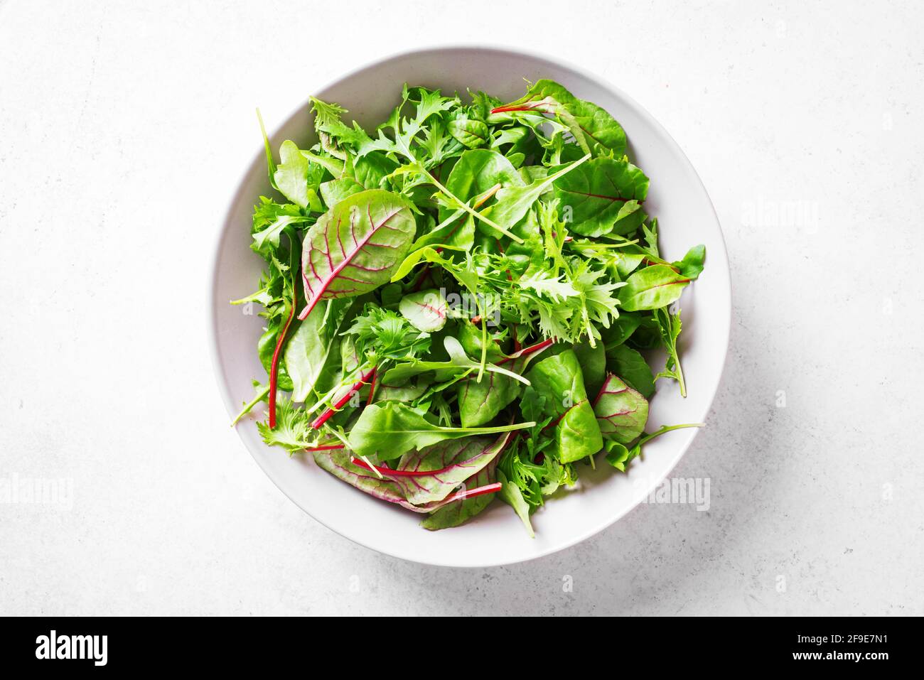 Insalata verde sana, foglie biologiche fresche mescolano insalata con rucola, bietola svizzera e lattuga su sfondo bianco, vista dall'alto, spazio copia. Foto Stock