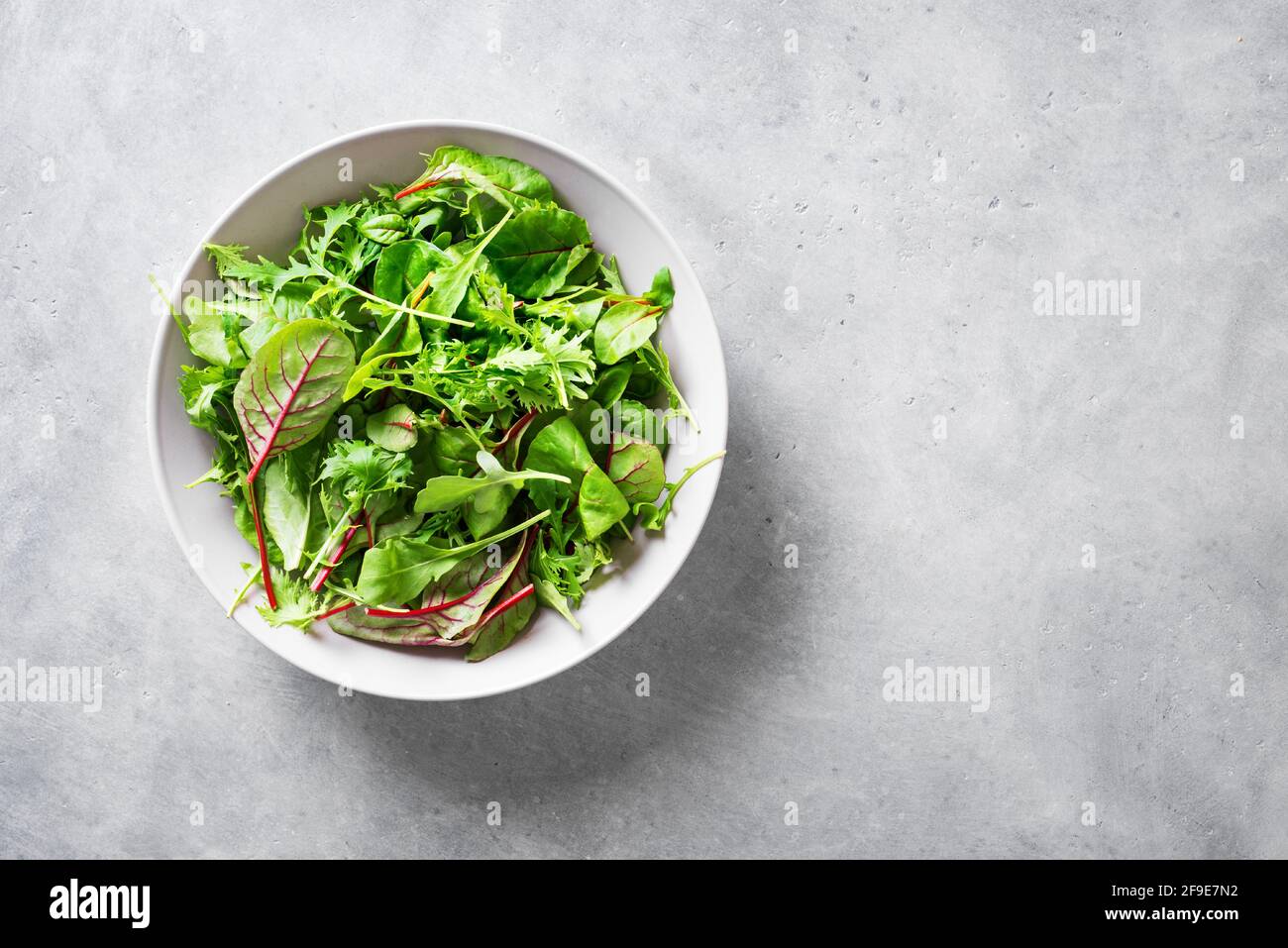 Insalata verde sana, foglie biologiche fresche mescolano insalata con rucola, bietola svizzera e lattuga, sfondo grigio chiaro, vista dall'alto, spazio copia. Foto Stock