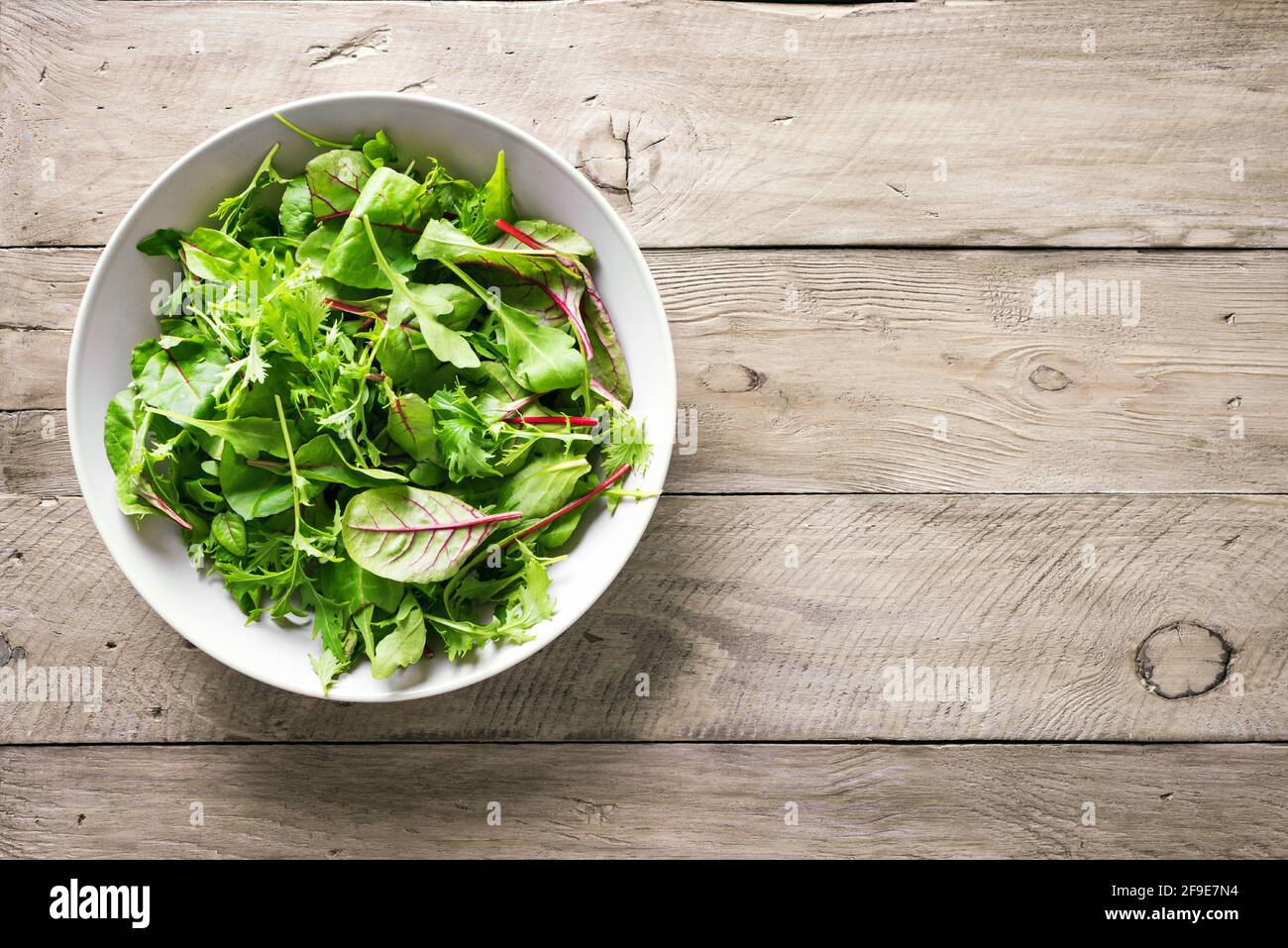 Insalata verde sana, foglie biologiche fresche mescolano insalata con rucola, bietola svizzera e lattuga, sfondo in legno, vista dall'alto, spazio copia. Foto Stock