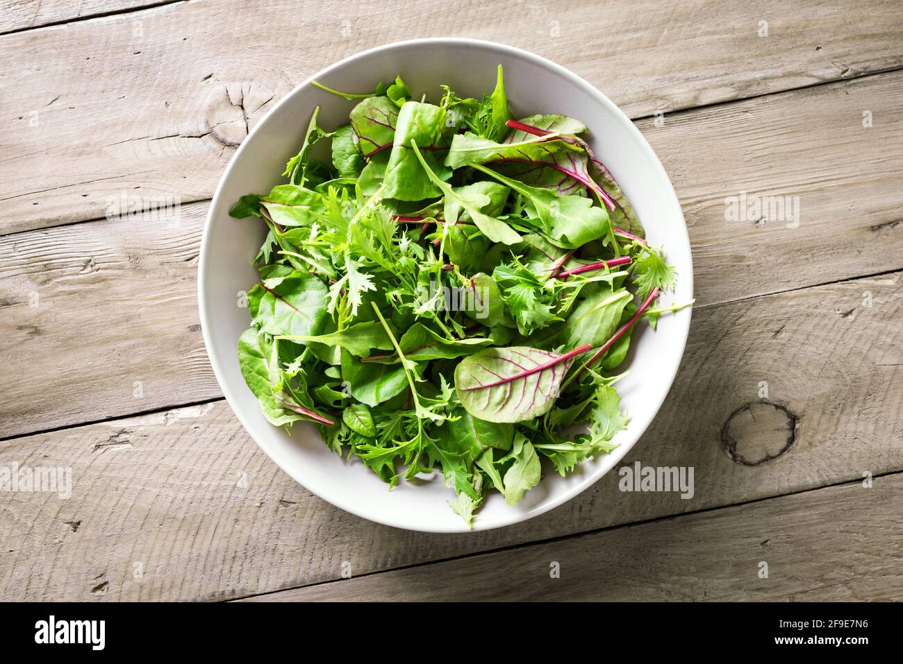Insalata verde sana, foglie biologiche fresche mescolano insalata con rucola, bietola svizzera e lattuga, sfondo in legno, vista dall'alto, spazio copia. Foto Stock