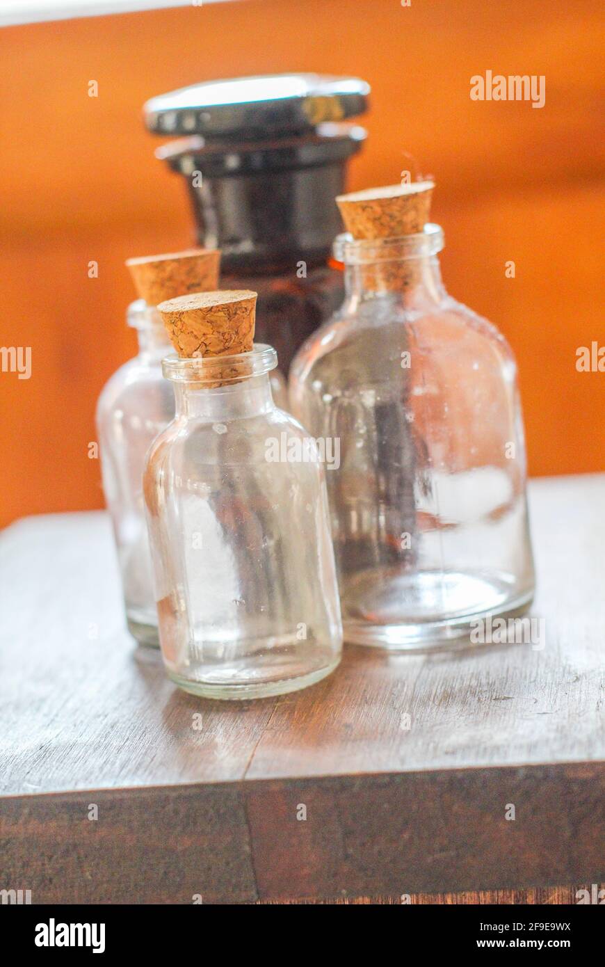 Un primo piano delle quattro bottiglie di vetro con tappi sopra il tavolo di legno Foto Stock