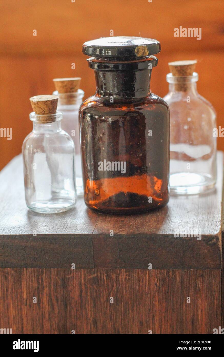 Un primo piano delle quattro bottiglie di vetro con tappi sopra il tavolo di legno Foto Stock