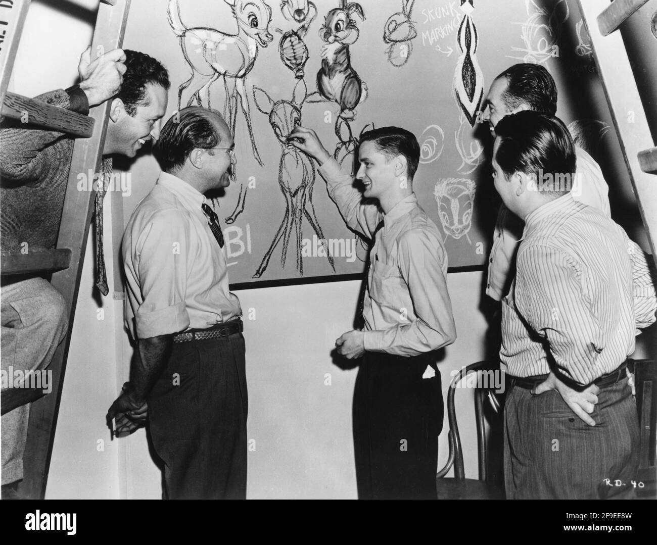 L'animatore JOHN LOUNSBERRY disegna schizzi di ''BAMBI'' sul muro della Scuola d'Arte, guardato dal direttore artistico GORDON WILES ALFRED WERKER e dagli sceneggiatori al PERKINS e TED SEARS sul set candid durante le riprese di sequenze d'azione dal vivo per IL regista RILUTTANTE DRAGON 1941 DI WALT DISNEY (Sequenze di azione dal vivo) ALFRED L. WERKER registi (sequenze di animazione) Hamilton Luske Jack Cutting Ib Uwerks e Jack Kinney sulla base della storia di Kenneth Grahame Walt Disney Productions / RKO radio Pictures Foto Stock