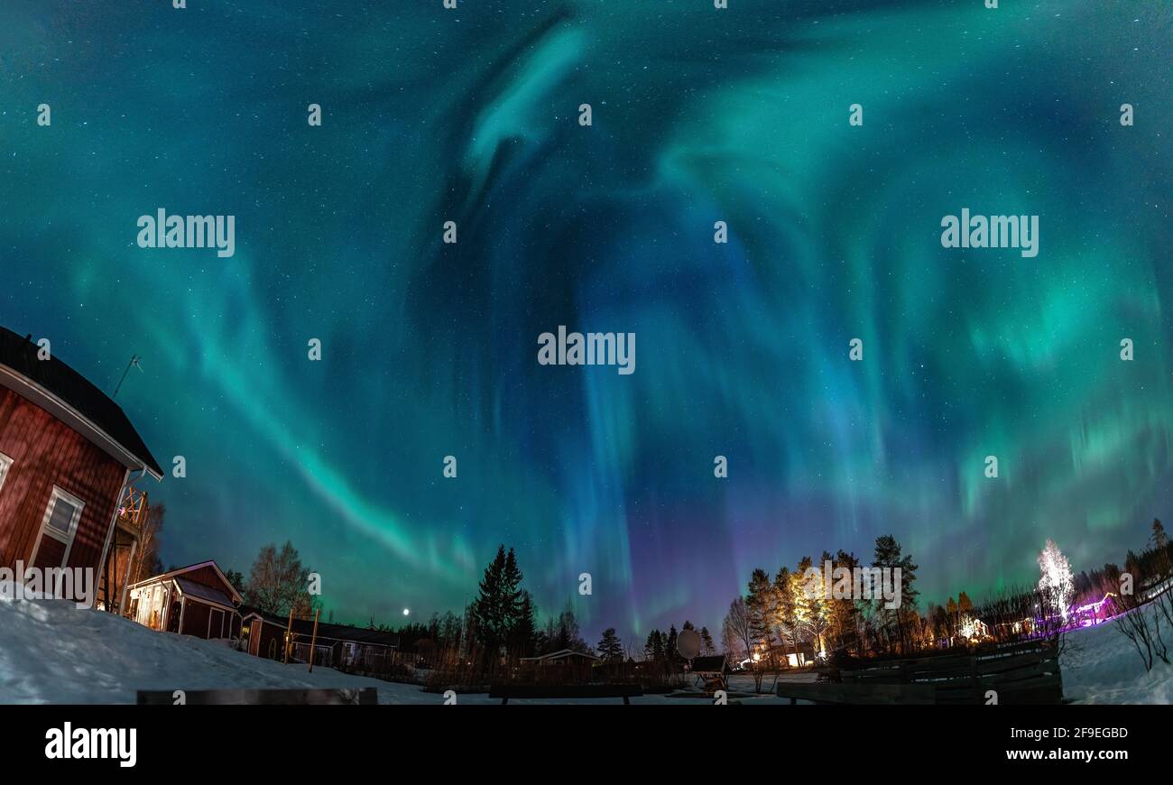 L'aurora boreale nel cielo stellato splende sopra la campagna svedese nel paesaggio settentrionale. Verde e blu Aurora Borealis strisce ricurve Foto Stock